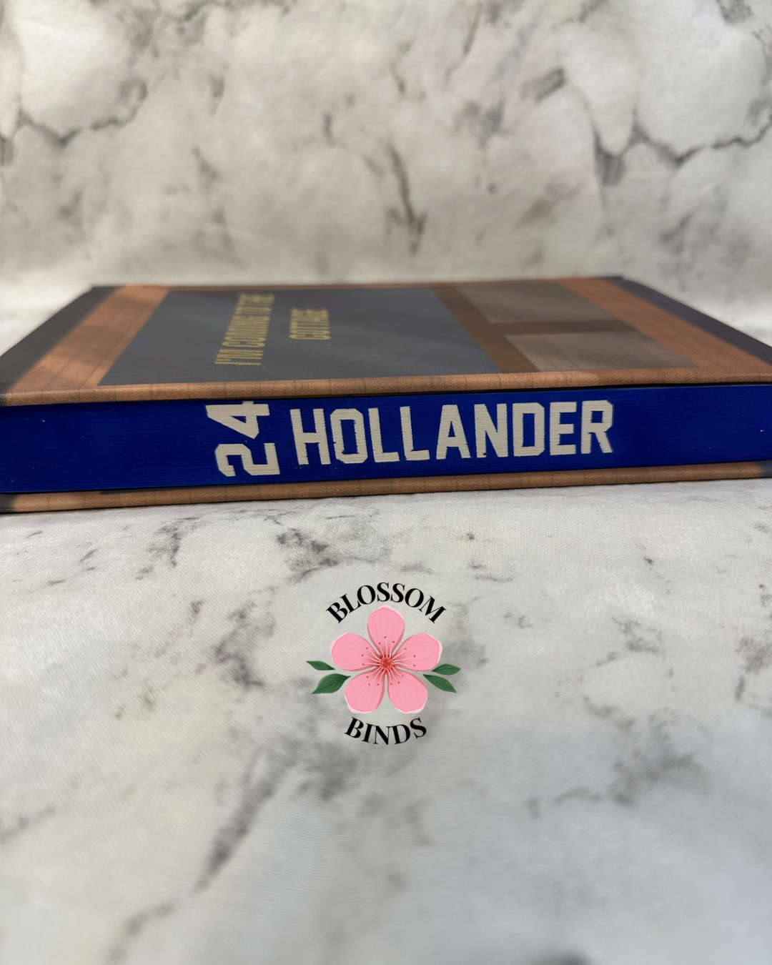 Book with '24 Hollander' with a visible brand logo on a marble background