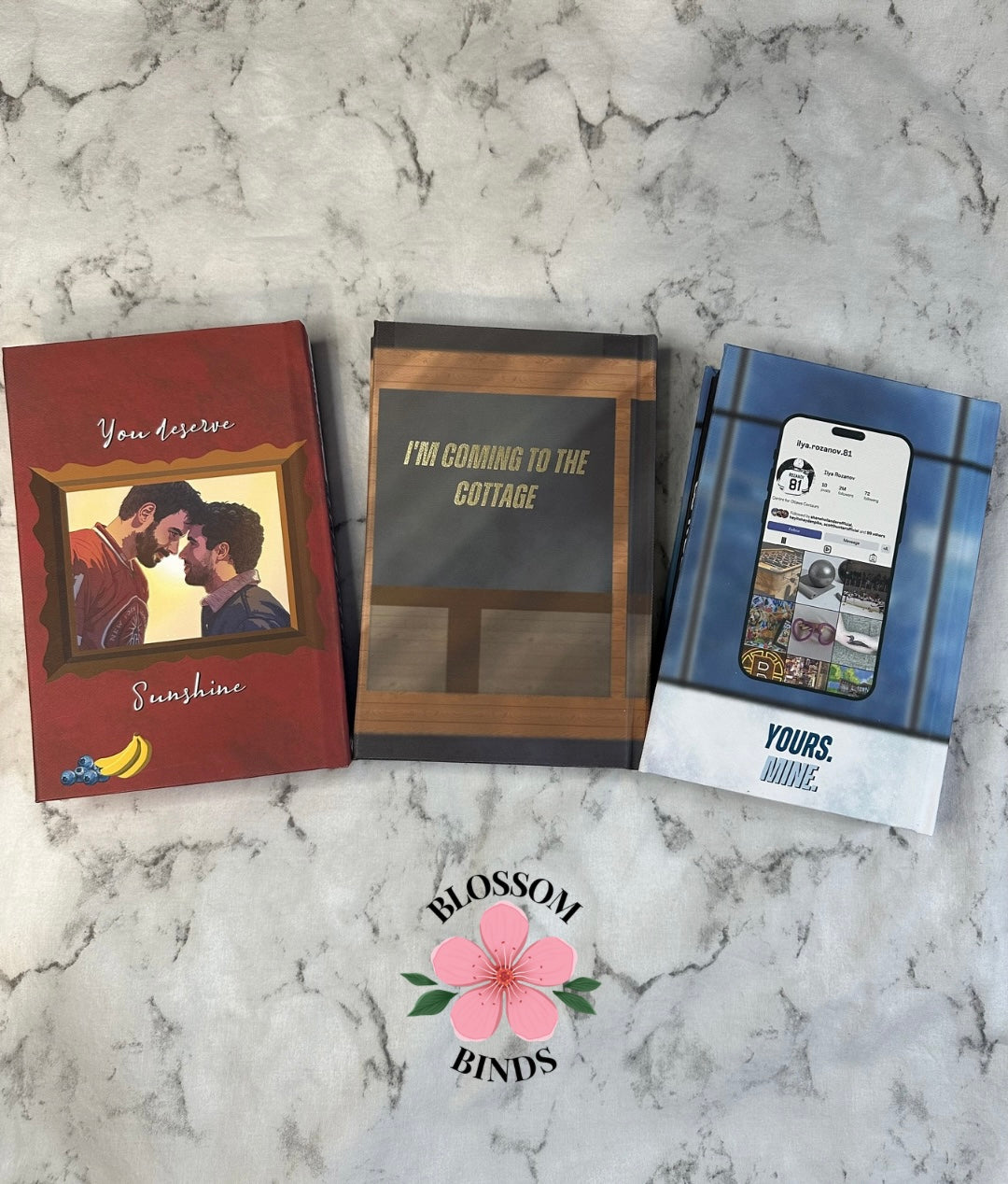 Three books on a marble surface with 'Blossom Binds' branding.