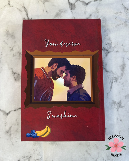 Red book with a couple illustration and 'You deserve sunshine' text on a marble background