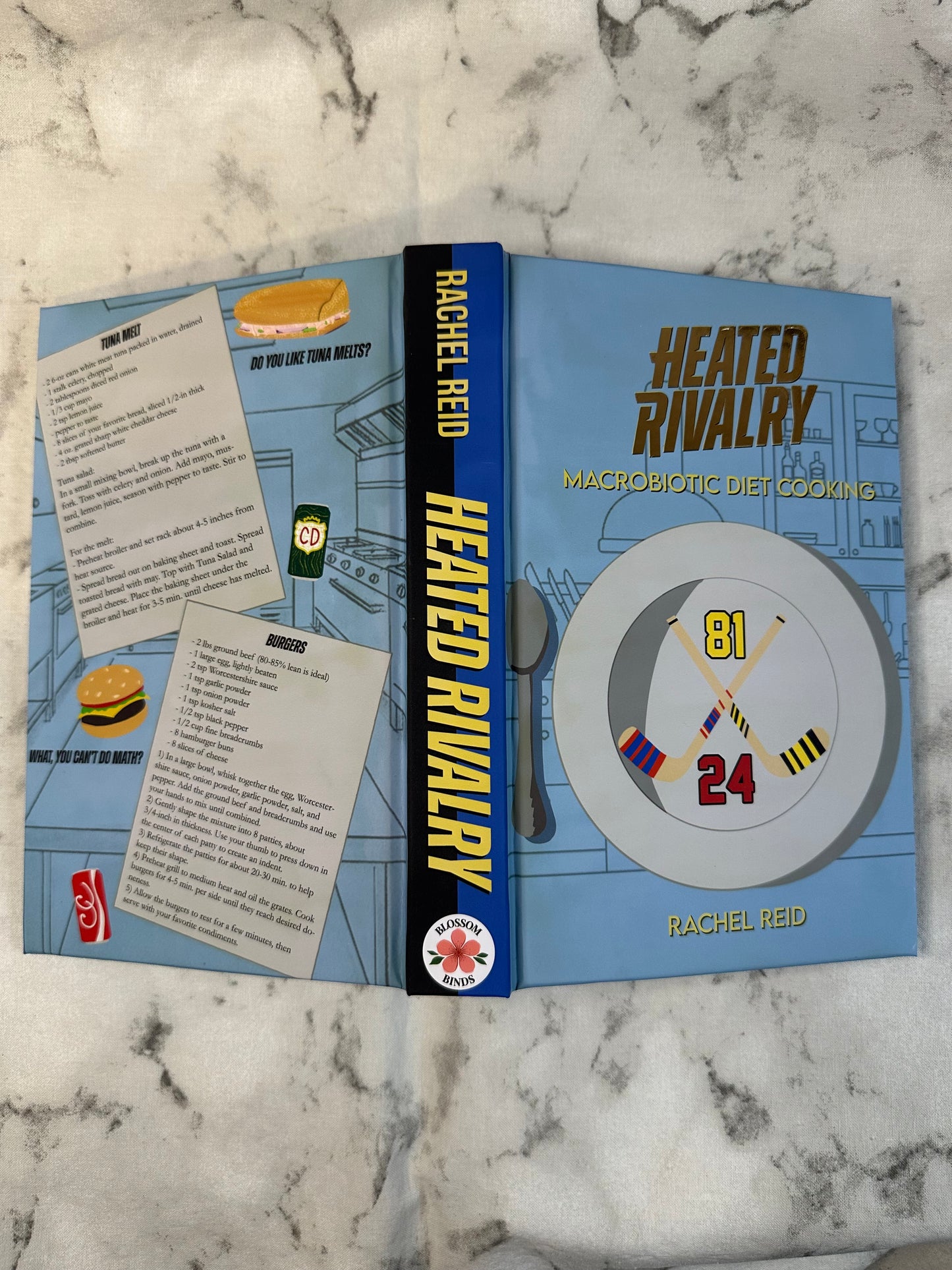 Book titled 'Heated Rivalry' by Rachel Reid on a marble surface