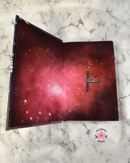 Open book with starry night design on a marble surface, featuring 'Blossom Binds' logo.