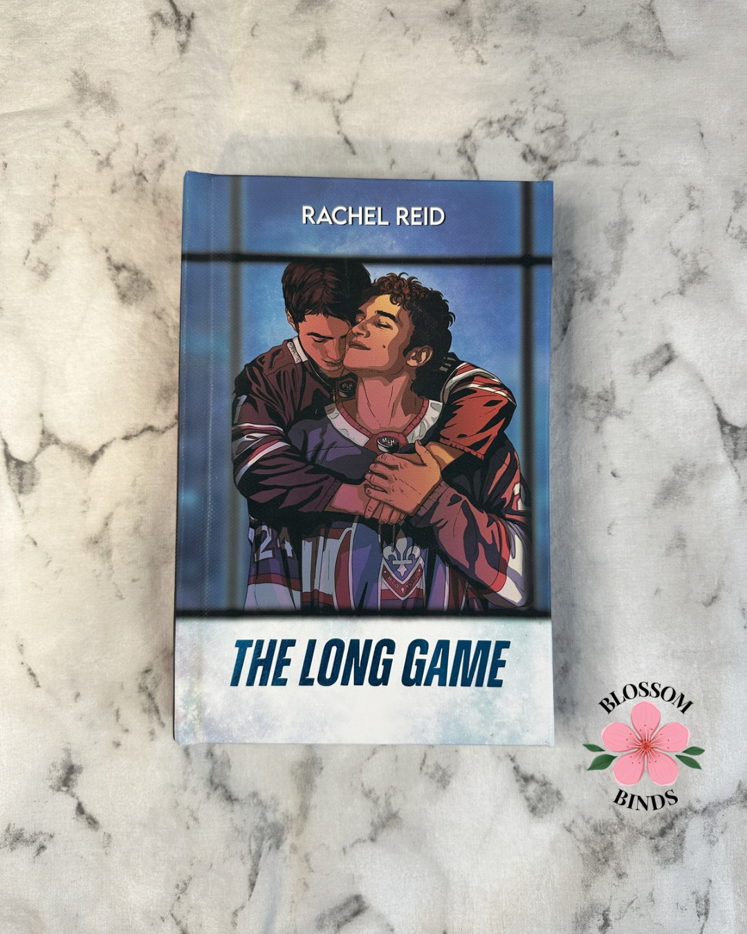 Book cover of 'The Long Game' by Rachel Reid on a marble surface with "Blossom Binds" branding.